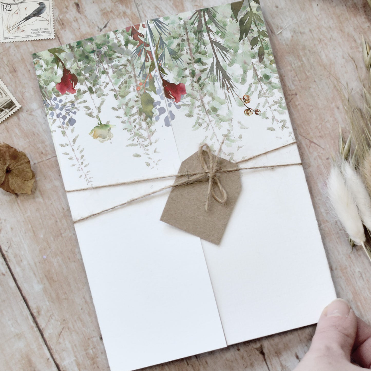 Rustic wedding invitations with green foliage and red flowers