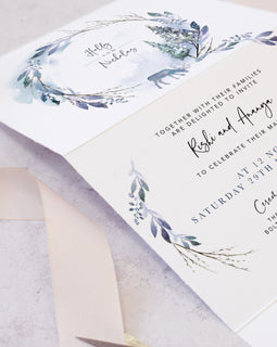 Winter wedding invites featuring pine trees and reindeer